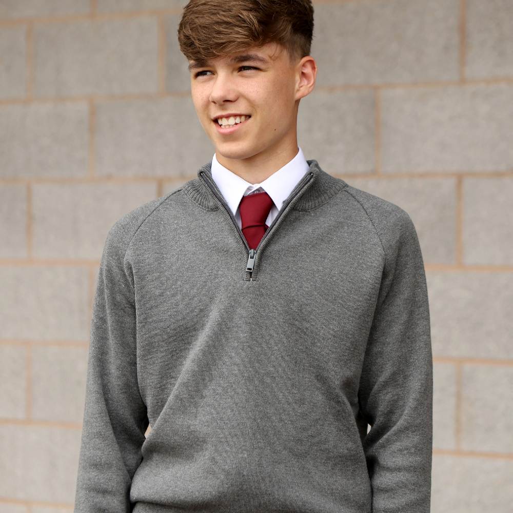 A school student in a grey Banner quarter zip pullover, shirt and tie 