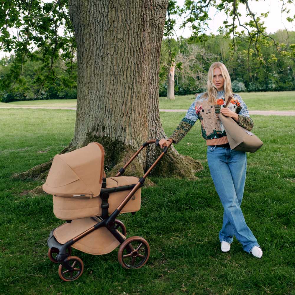 A woman stood in a park by a tree with a Bugaboo x Stella McCartney stroller 