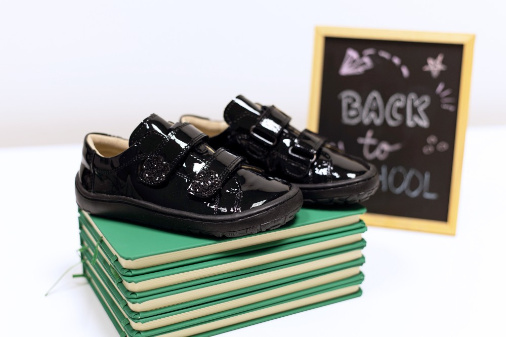 Children's black patent school shoes by Froddo displayed on green notebooks and a chalk board