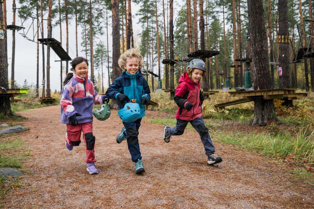 Children in outerwear running outside in a wood