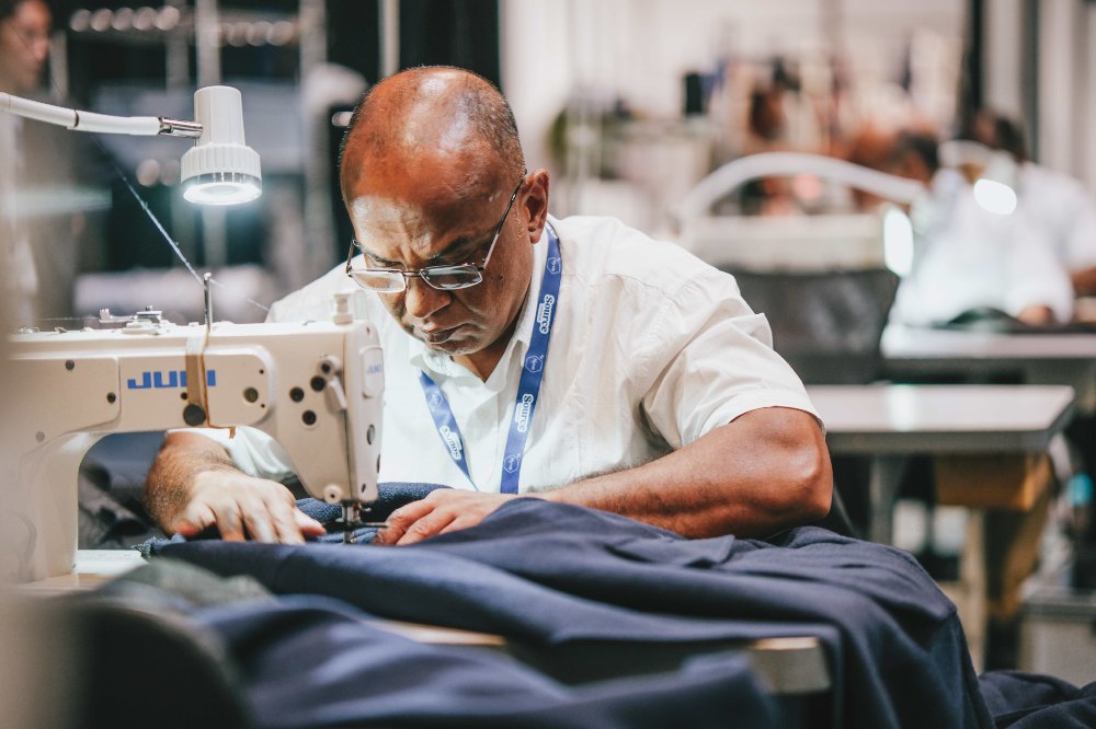 A man at a sewing machine in a UK clothing factory