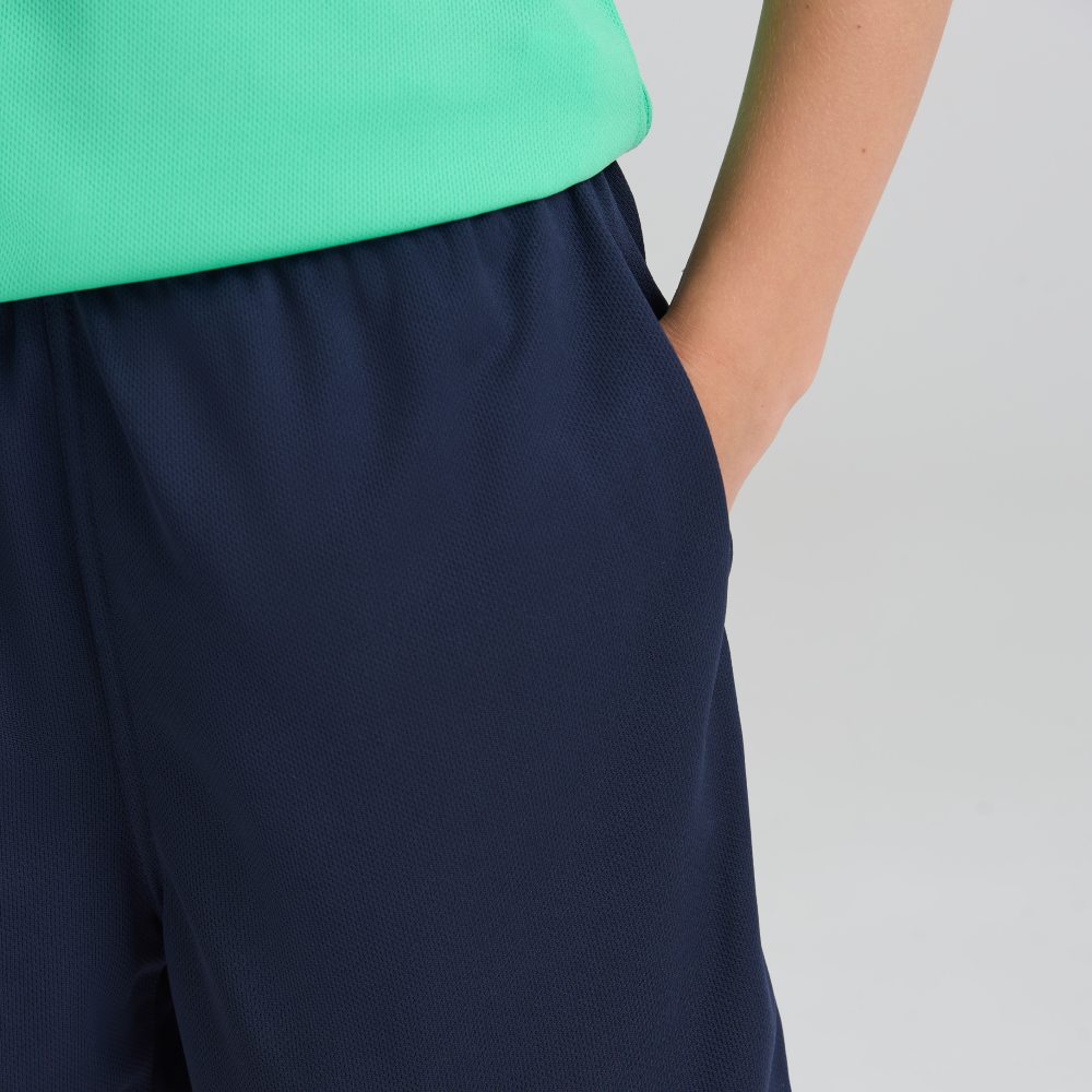 A close up of a child wearing blue shorts and a green T-shirt