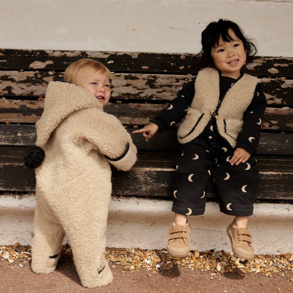 Two children by a bench wearing outfits from the Organic Zoo and BINIBAMBA limited edition Midnight collaboration 