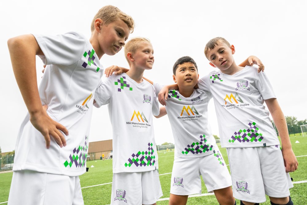 Four children in a scrum wearing sportswear 