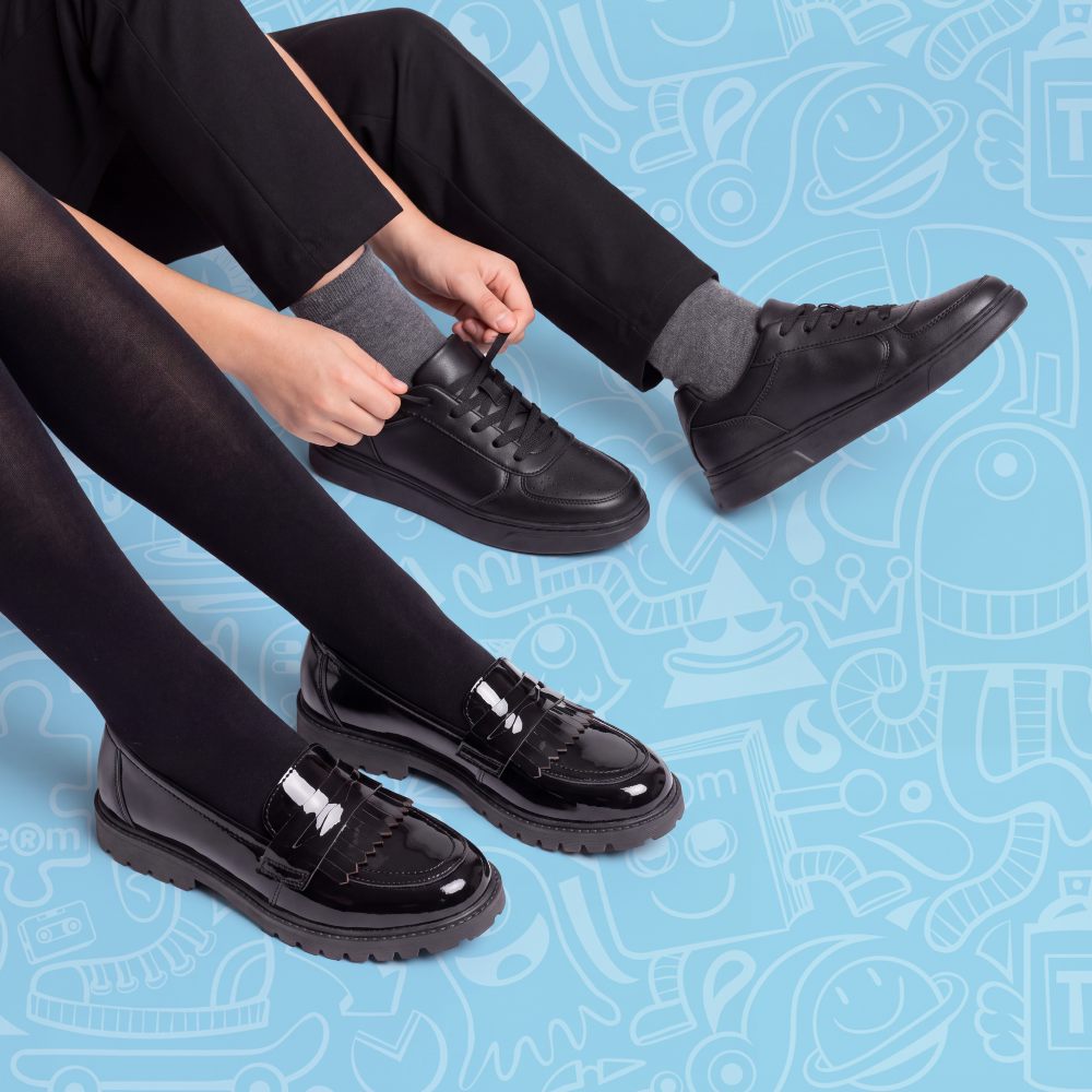 Children's feet shown wearing black school shoes against a blue background
