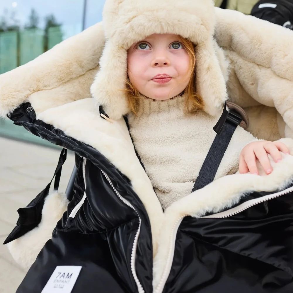 A child in a pram with a fluffy winter hat on by 7AM