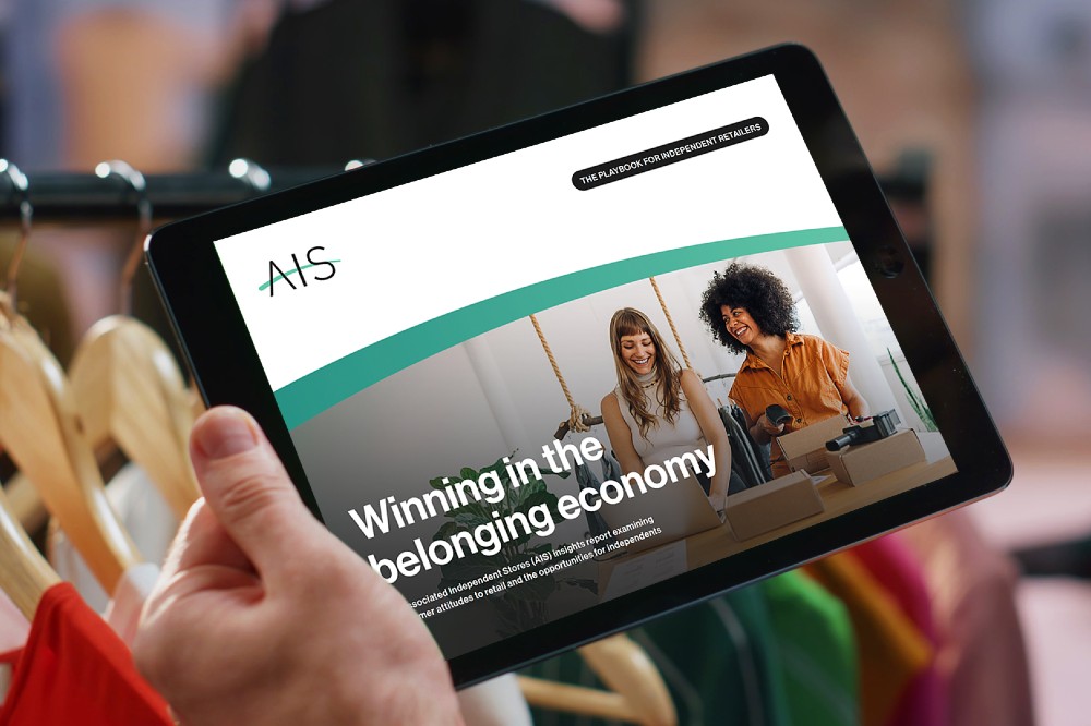 Someone in a clothes hop holding a tablet with the Winning in the belonging economy on the screen