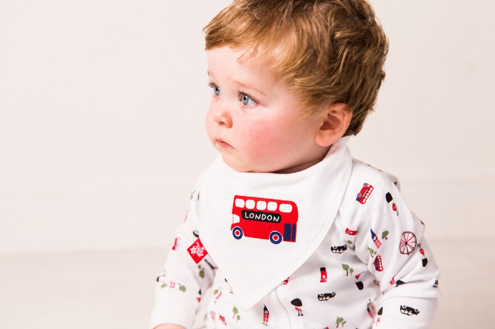 A baby in a London-themed bib and babygro by Blade & Rose