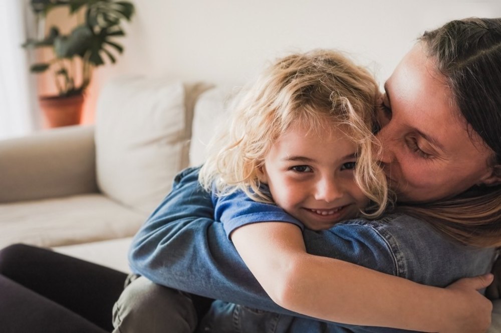 A woman sat on a sofa hugging a child to promote FTCT 