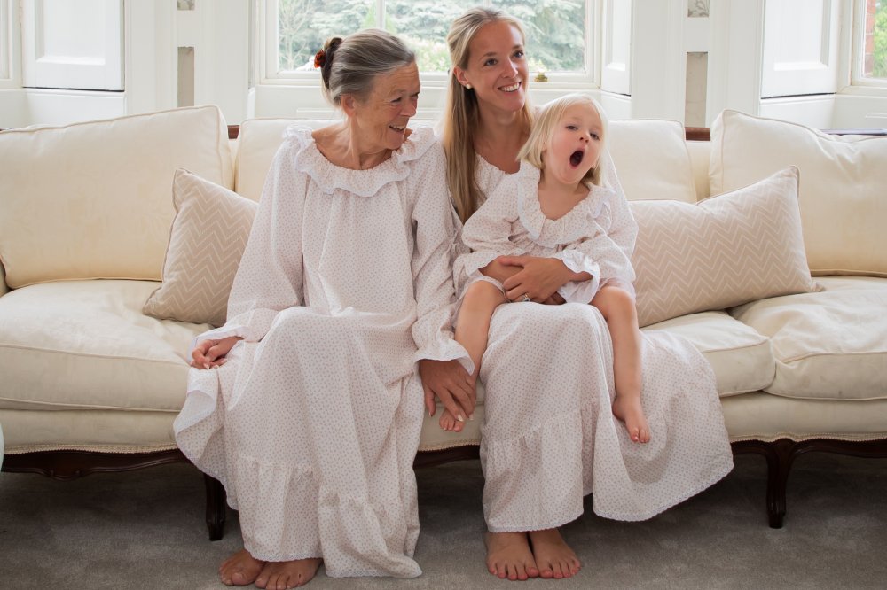 Two woman and a baby sat on a sofa wearing nightwear by Harriet Jane London