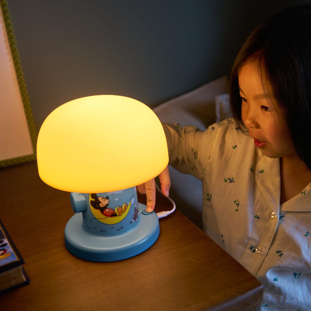 A girl turning off a Mickey Mouse Willow nightlight by Lumie 