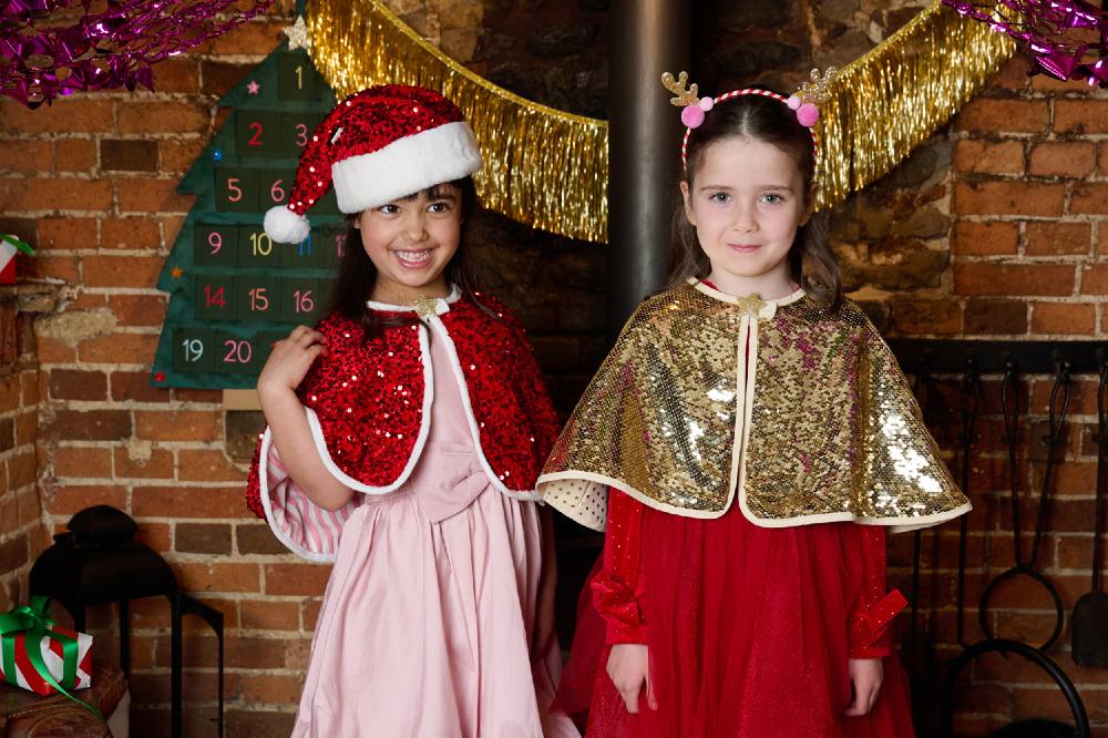 Two children stood in front of a fire place wearing Christmas outfits and accessories by Rockahula Kids
