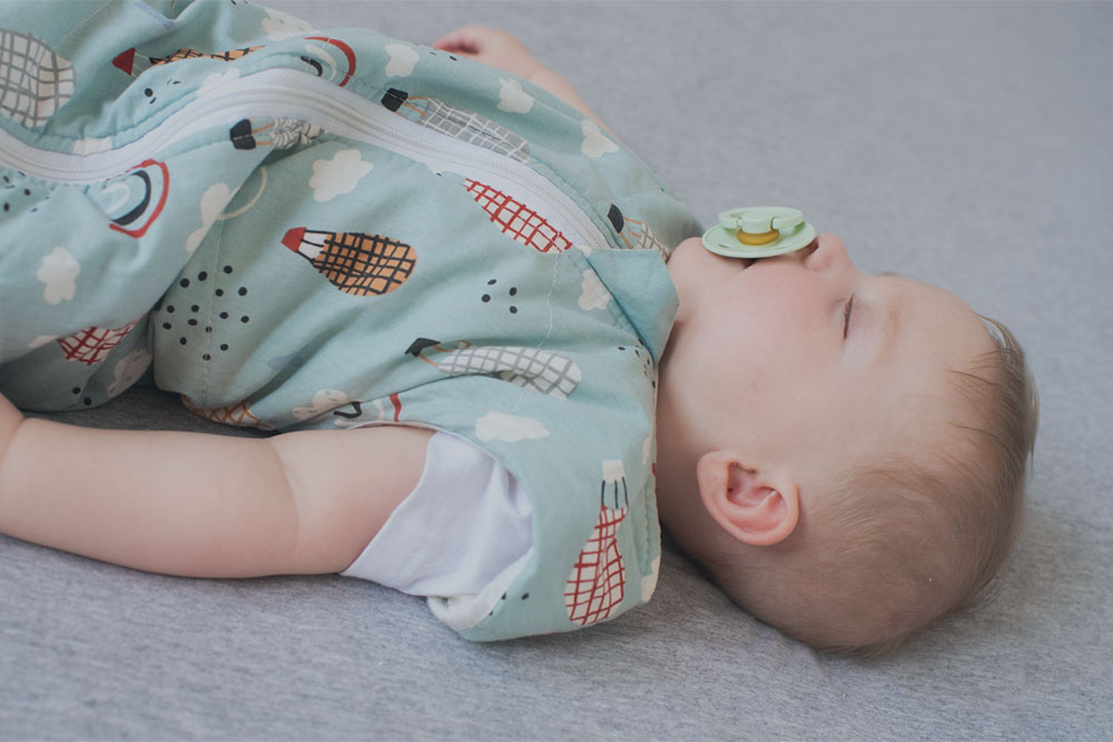 A baby laid down asleep in a cot